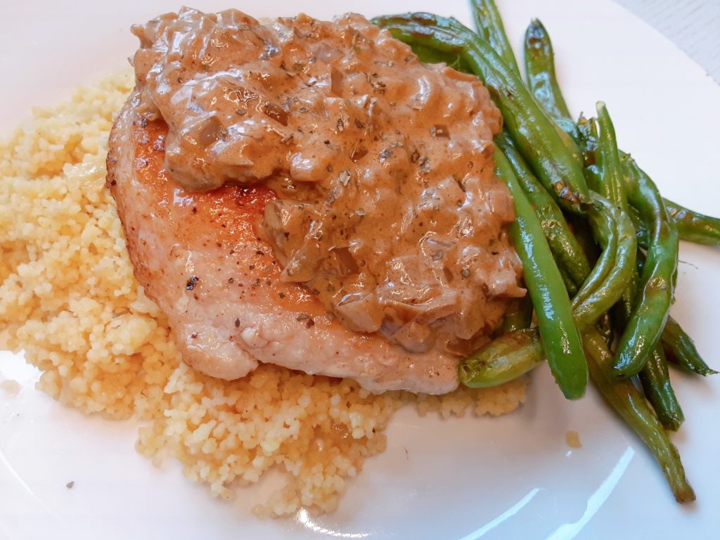 A deliciously tender and lean pork chop with a creamy, onion sauce served with couscous and green beans for a restaurant quality meal you can make at home for under $10!