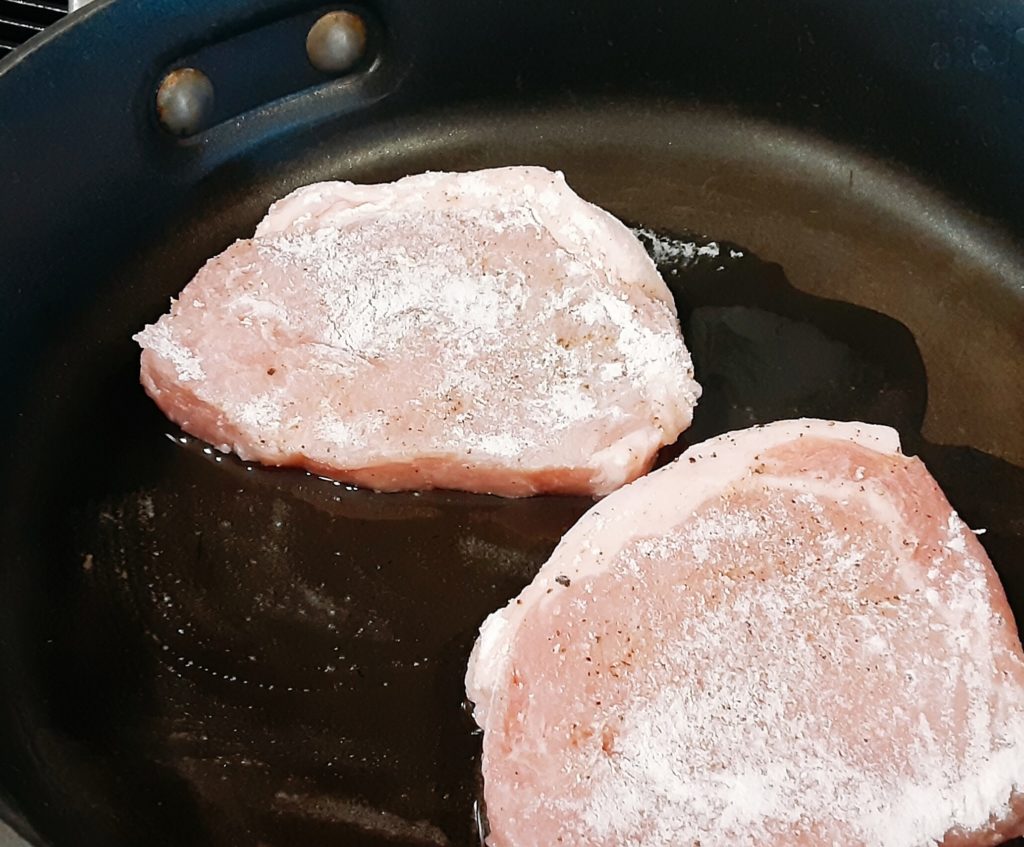pork chops cooking in pan