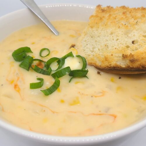 Corn chowder soup topped with scallions and served with toasted garlic baguette