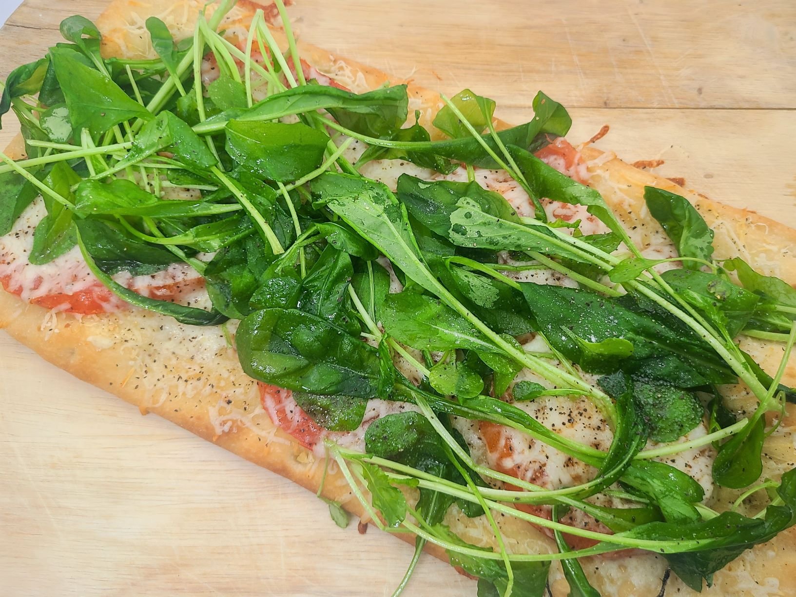 fresh ingredients with arugula and tomatoes on top of flatbreads