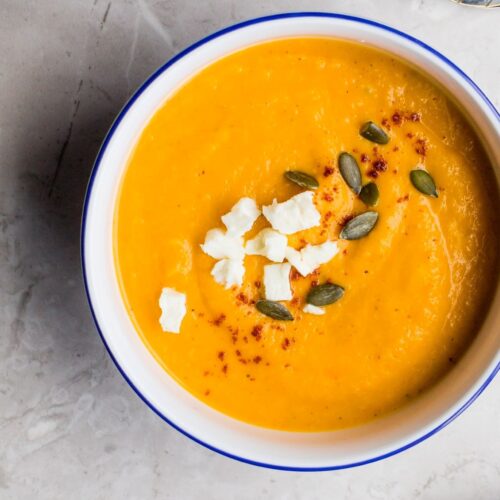 butternut squash soup recipe with vegetables and apple blended into a bowl topped with seeds