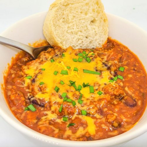 delicious ground turkey chili recipe with red beans in a white bowl topped with cheddar cheese